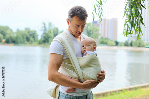 Tableau sur toile Father carrying his son in sling outdoors