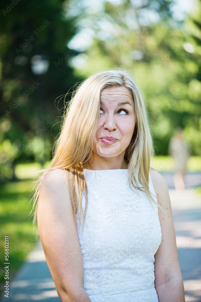 Naklejka premium Beautiful young blond woman in a white dress outdoors