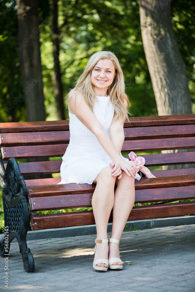 Young woman sitting on the bench in park Young woman sitting on the bench in park