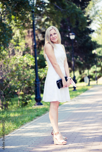 Beautiful young blond woman in a white dress outdoors