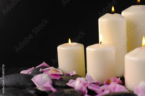 White candle and rose petals and stones