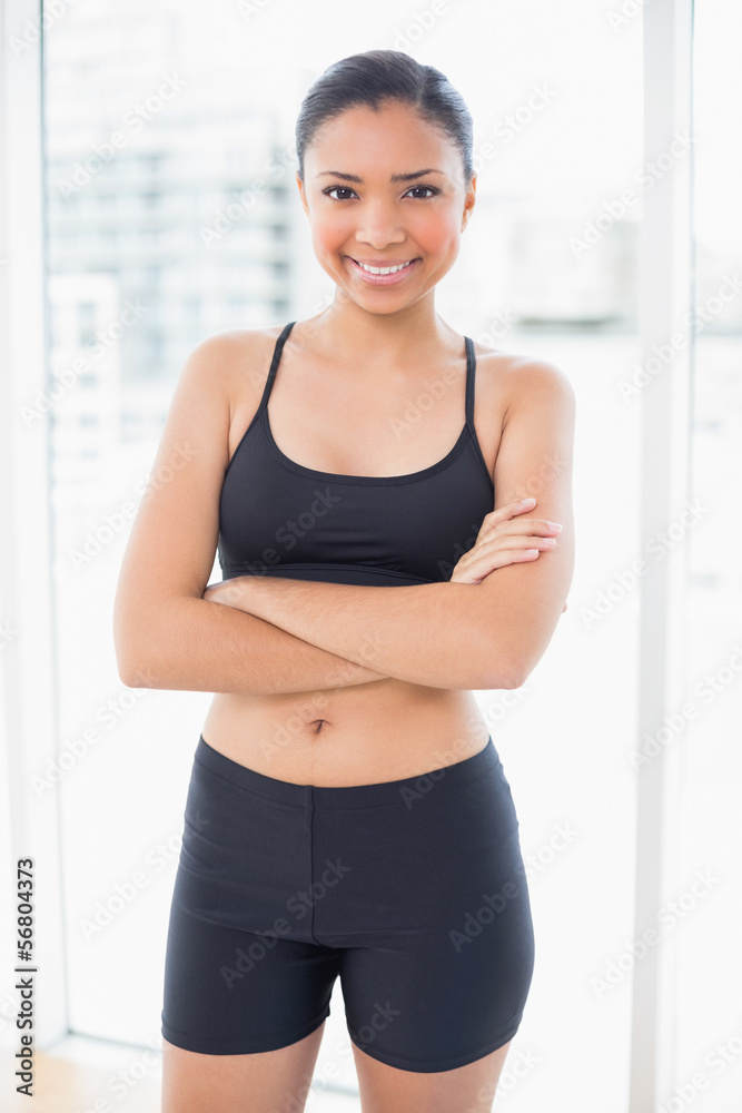 Smiling dark haired model in sportswear posing with crossed arms Smiling dark haired model in sportswear posing with crossed arms