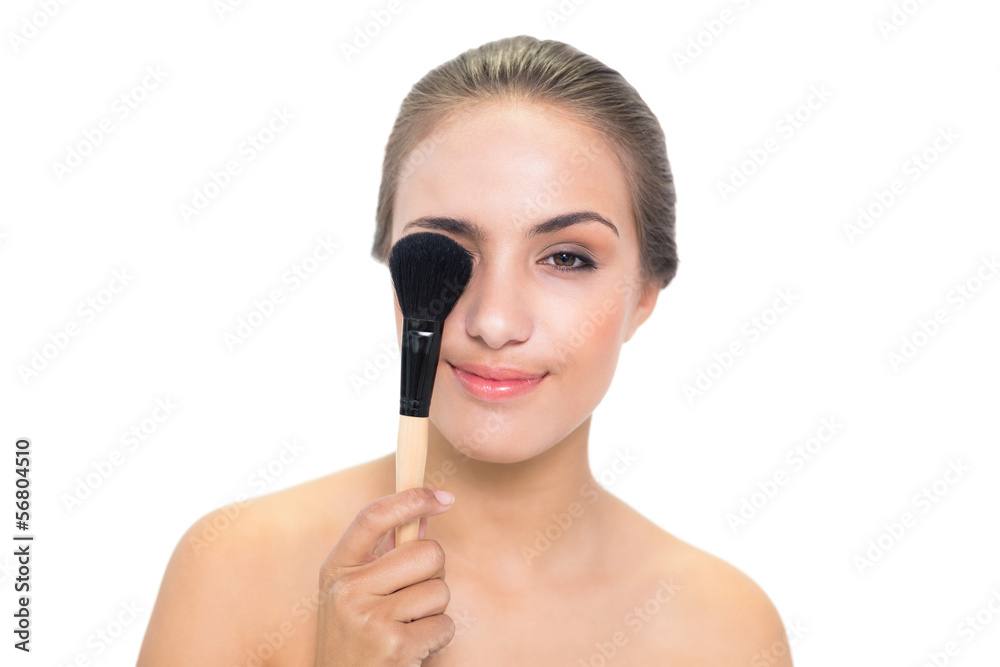 Smiling young brunette woman holding a powder brush Smiling young brunette woman holding a powder brush