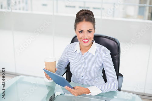 Smiling businesswoman holding tablet and disposable cup