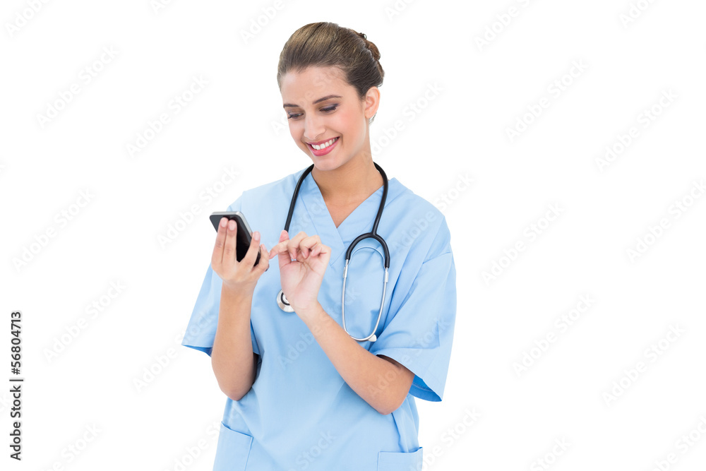 Content brown haired nurse in blue scrubs using a mobile phone Content brown haired nurse in blue scrubs using a mobile phone