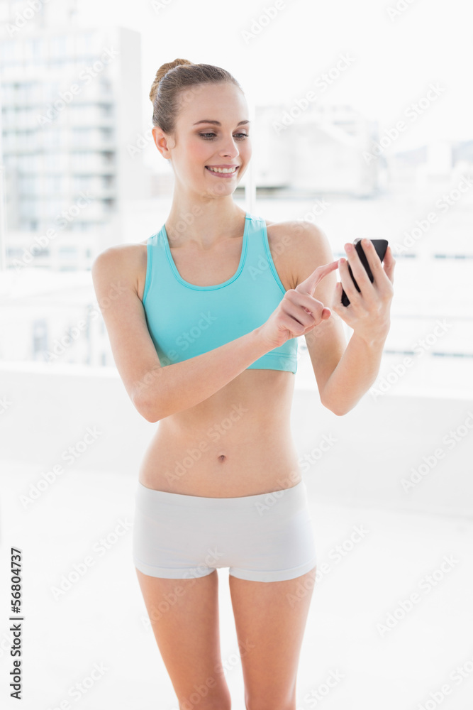 Sporty cheerful woman using smartphone
