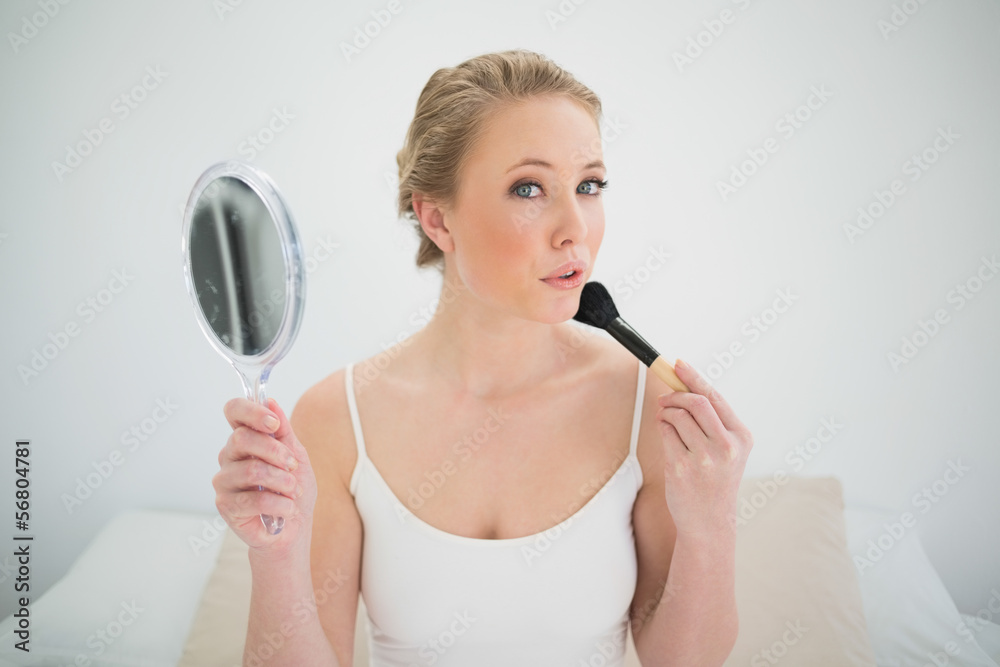 Natural blonde holding mirror and using brush Natural blonde holding mirror and using brush