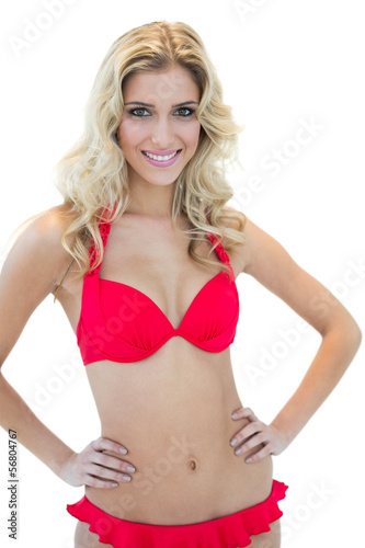 Openly smiling blonde model posing with hands on hips in red bik © lightwavemedia