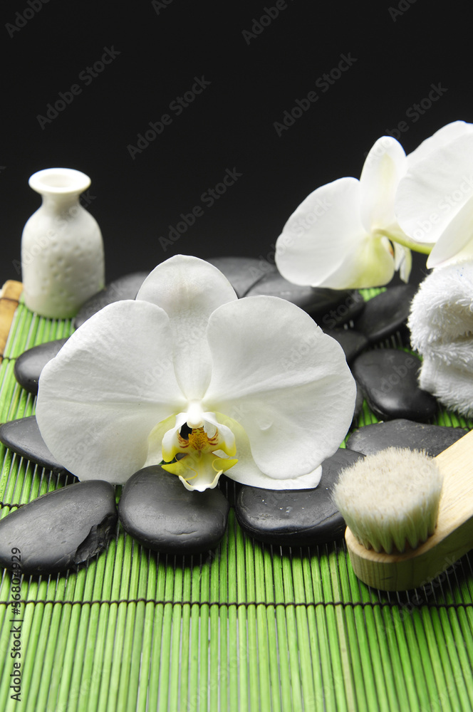 white orchid with pebble stone and towel on green mat white orchid with pebble stone and towel on green mat