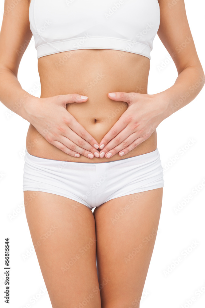 Slim young woman touching her belly with her hands Slim young woman touching her belly with her hands