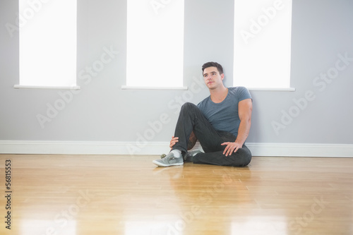Fototapeta Naklejka Na Ścianę i Meble -  Thinking handsome man leaning against wall sitting on the floor