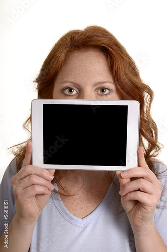Hübsche rothaarige Frau hält Mini Tablet PC vors Gesicht