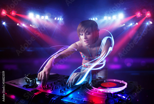 Disc jockey girl playing music with light beam effects on stage photo