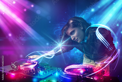 Energetic Dj girl mixing music with powerful light effects