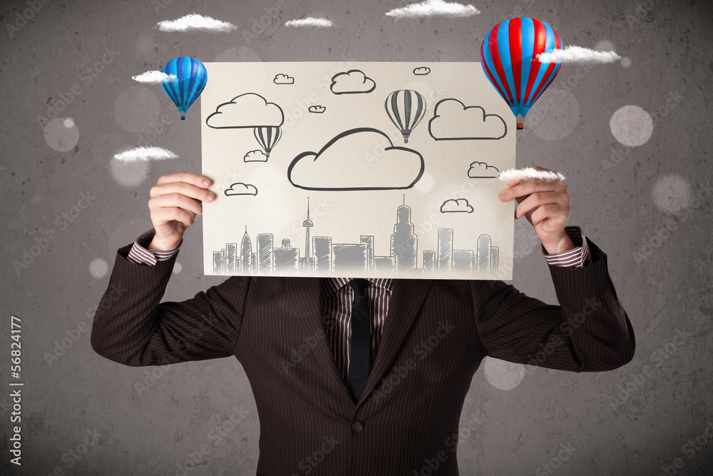 Businessman holding a cardboard with cityscape in front of his h Businessman holding a cardboard with cityscape in front of his h