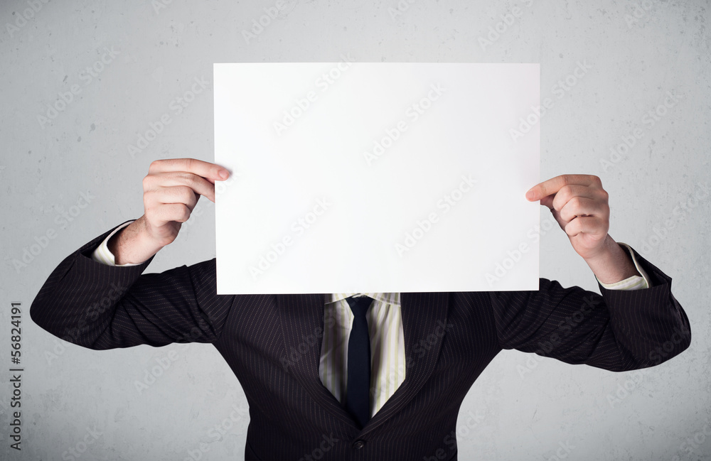 Businessman holding in front of his head a paper with copy space Businessman holding in front of his head a paper with copy space