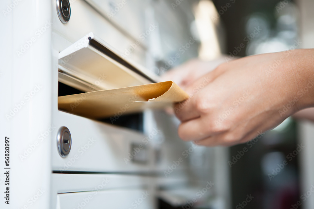 Woman putting envelope in mailbox - obrazy, fototapety, plakaty 