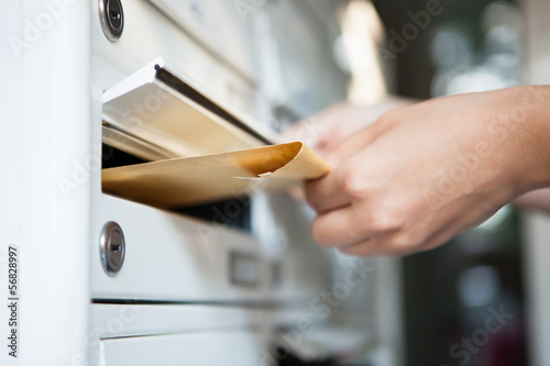 Fotografiet Woman putting envelope in mailbox