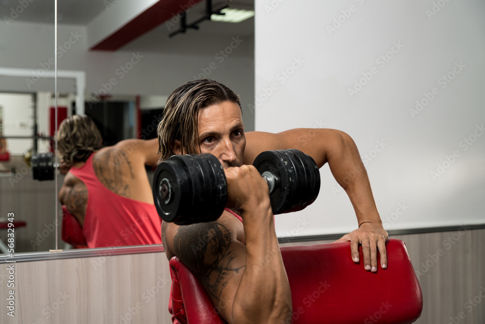 Man In The Gym Exercising Biceps With Dumbbells