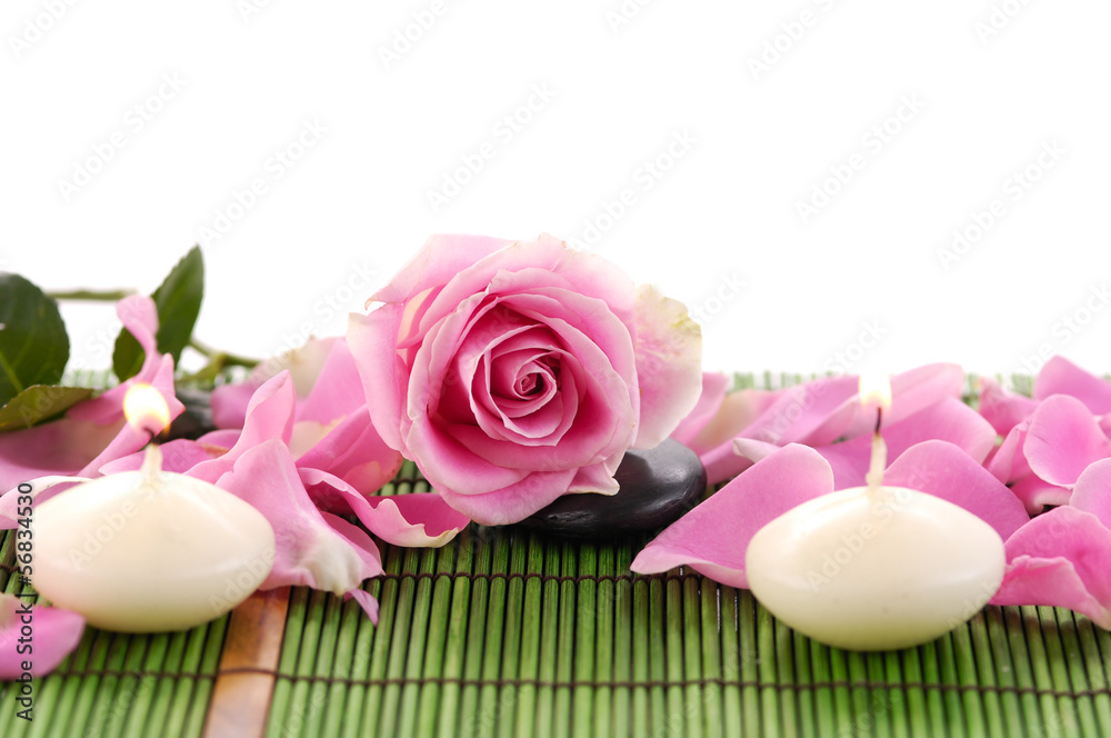 Rose with petals and candle on green mat