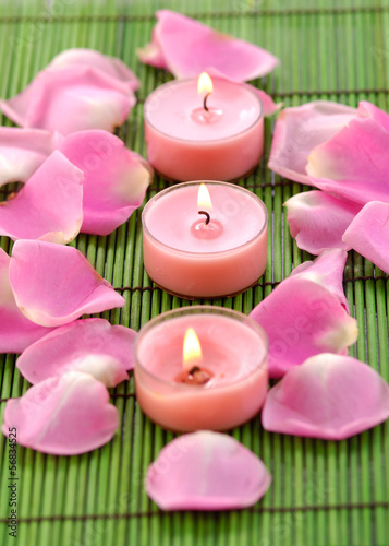 Row of three red candles with rose petals on mat