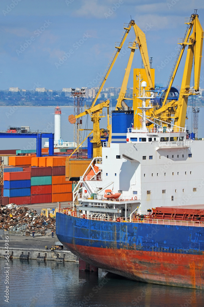 Fototapeta premium Container stack and cargo ship under crane bridge