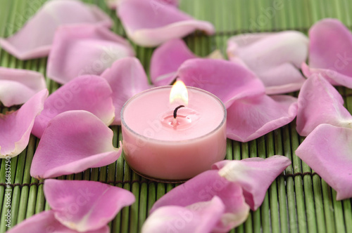 Spa composition of rose petals and candle on green mat