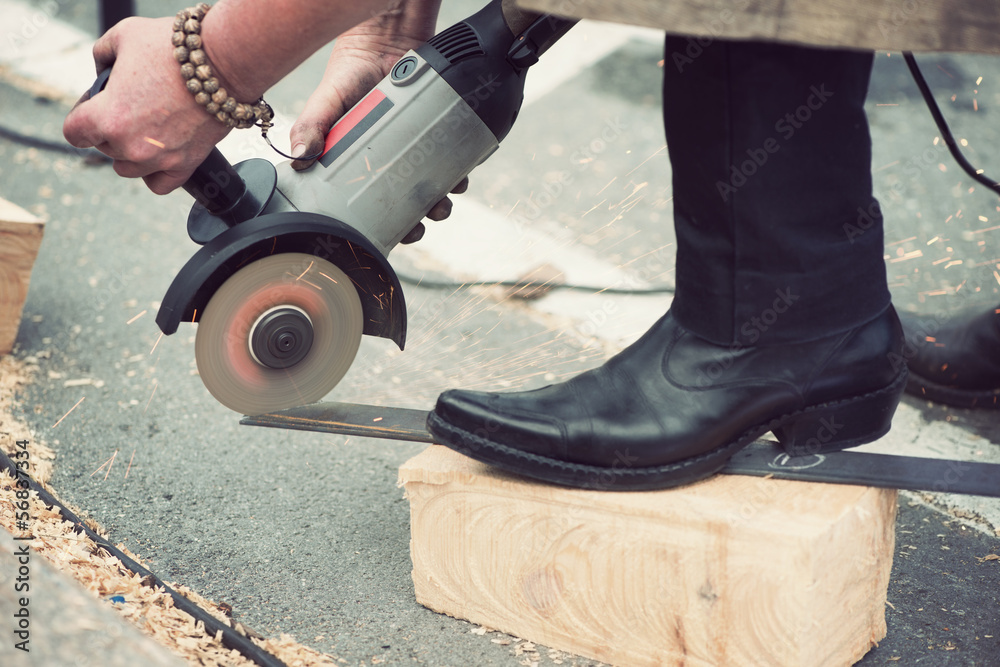 Obraz premium Unrecognizable female blacksmith grinding a metal plate