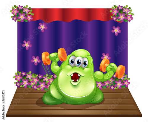 A stage with a green monster exercising in the center