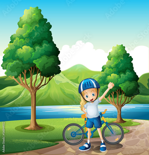 A young female biker standing near the river
