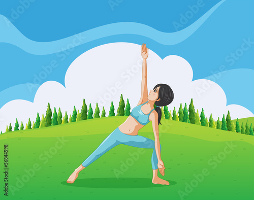 A slim girl doing yoga at the top of the hill