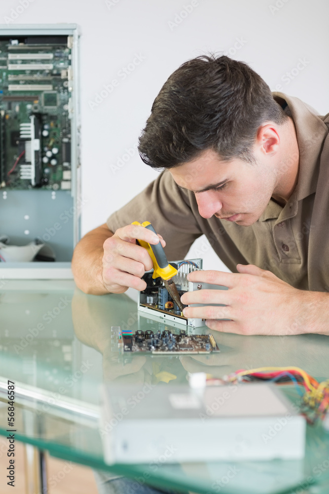 Obraz premium Handsome focused computer engineer repairing hardware with plier