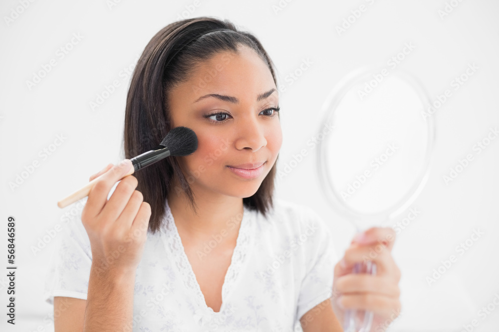 Attentive young dark haired model applying powder on her face Attentive young dark haired model applying powder on her face