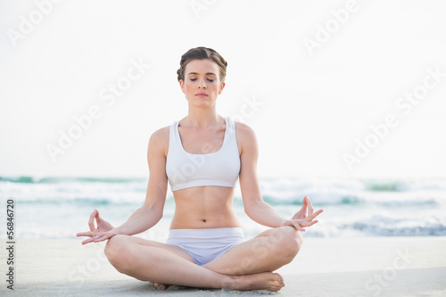 Peaceful slim brown haired model in white sportswear meditating