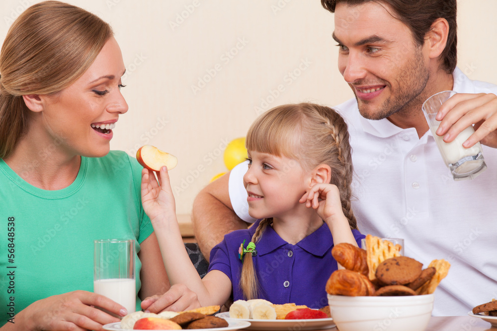 Small girl is feeding her mother with an apple, Small girl is feeding her mother with an apple,