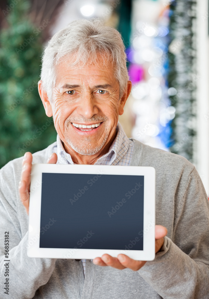 Happy Man Displaying Digital Tablet In Christmas Store Happy Man Displaying Digital Tablet In Christmas Store