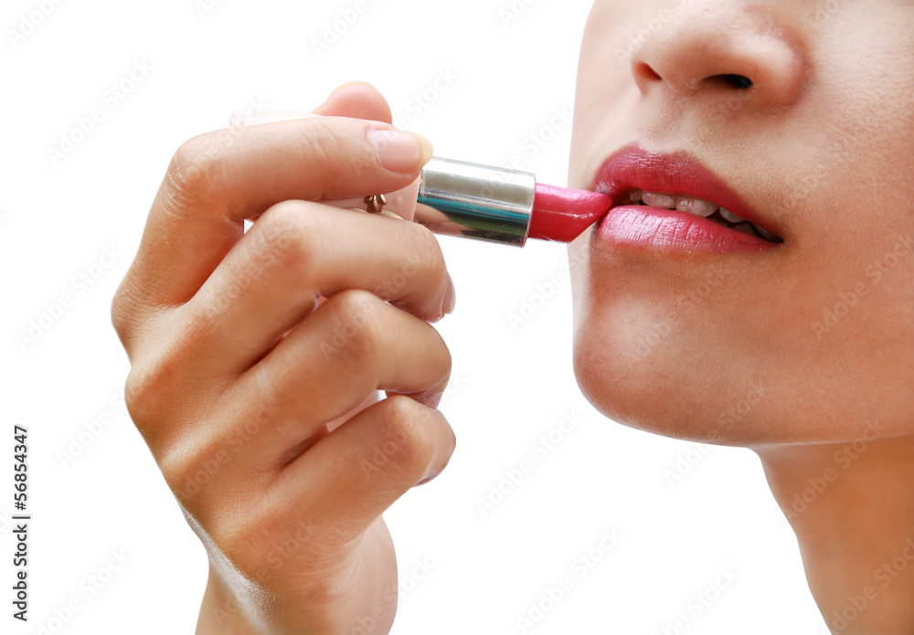 beautiful woman is applying her lips with pink lipstick on white