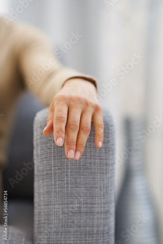 Closeup on hand of young housewife sitting on couch