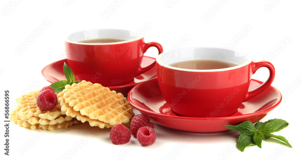 Fototapeta premium Cups of tea with cookies and raspberries isolated on white