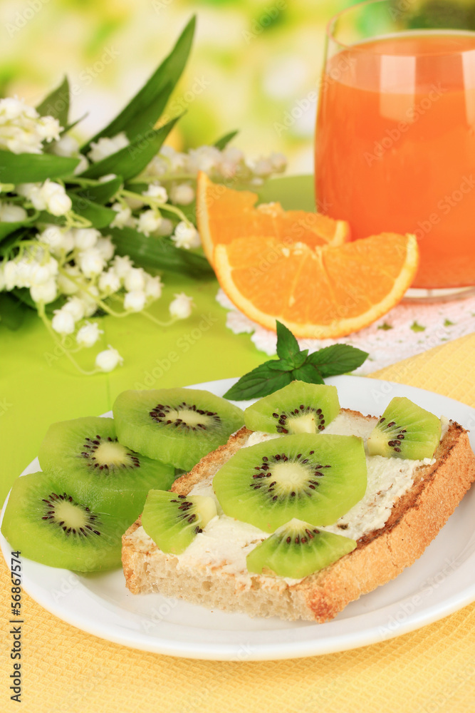 Delicious toast with kiwi on table on bright background
