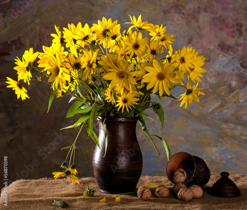 Bunch of bright yellow flowers (rudbeckia) in brown vase and wal