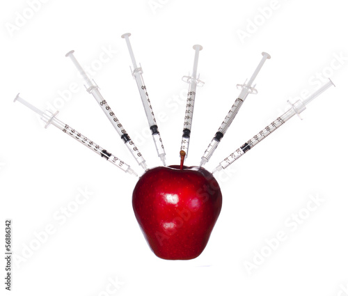 Genetically modified red apple and syringes isolated.