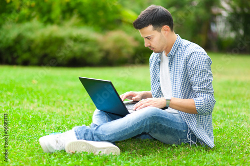 Young man using his laptop on the grass