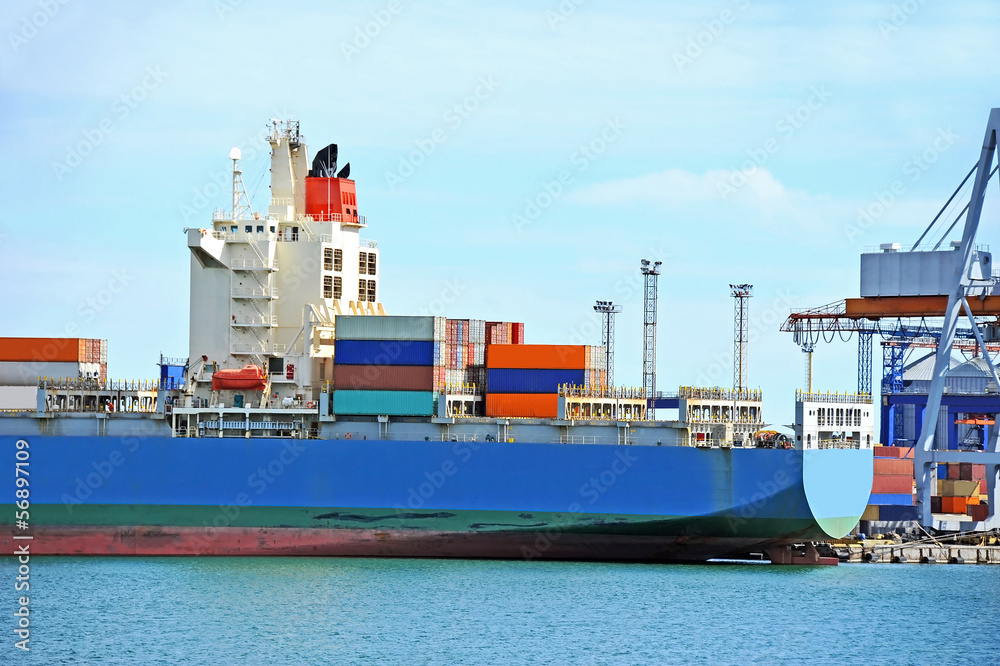 Fototapeta premium Container stack and cargo ship under crane bridge
