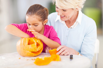 granddaughter helping grandmother making halloween pumkin