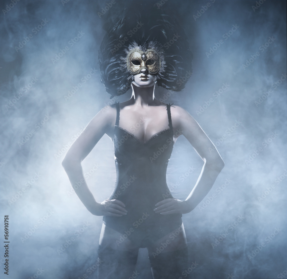 Fashion shoot of a young woman in a mask posing in the mist