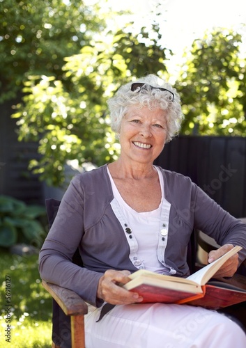 Elderly woman with novel in garden