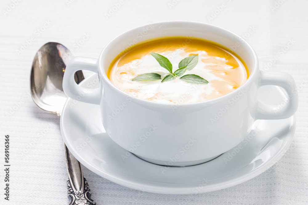 Pumpkin soup with basil on served table Pumpkin soup with basil on served table