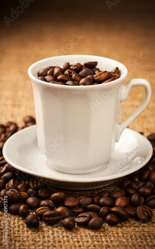 Roasted coffee beans in a cup on burlap background