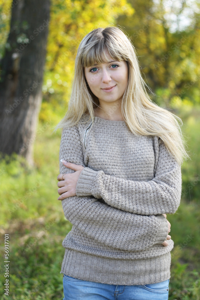 Portrait of young blonde woman in sweater walking in autumn Portrait of young blonde woman in sweater walking in autumn